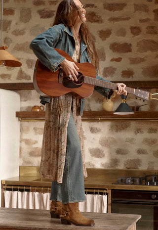 A woman stands in a rustic kitchen setting