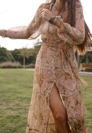  posing outdoors with her arms raised in front of a modern house and grassy lawn.