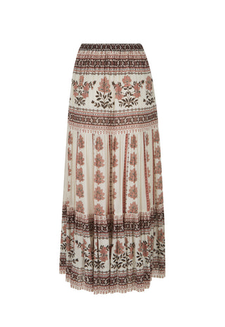 A woman modeling a bohemian-style two-piece outfit featuring a white sleeveless lace-trimmed top and a long cream maxi skirt with brown floral and geometric patterns